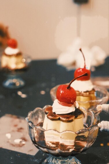 A dessert with a cherry on top, served in a glass bowl. 1