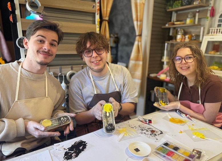 Three people engaged in a craft activity with various art supplies on a table. 2