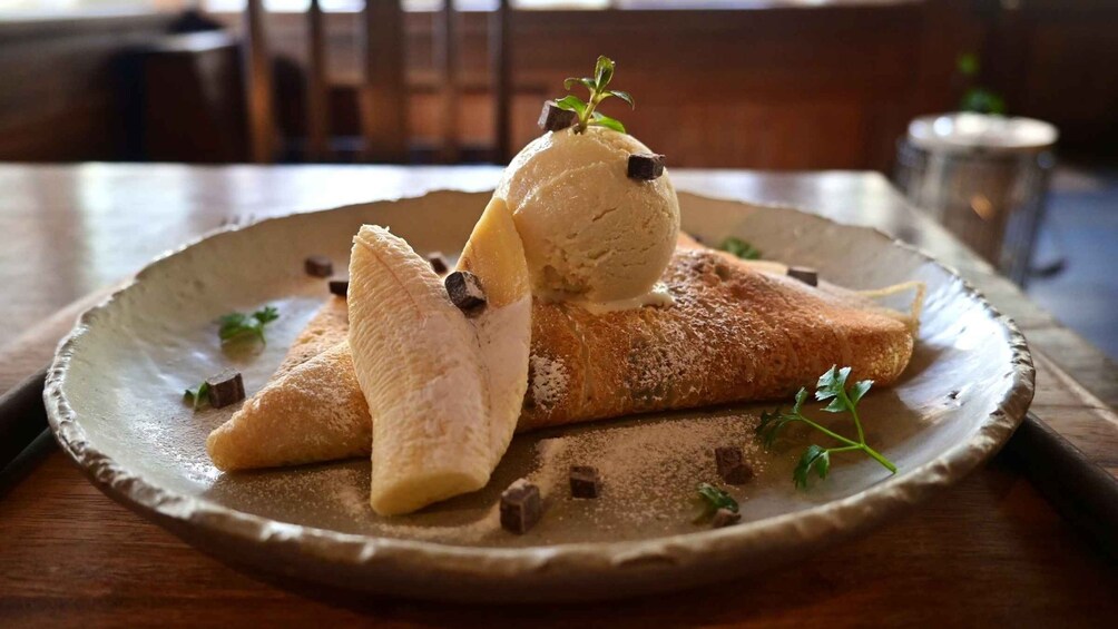A plate with a banana, a scoop of ice cream, and a pastry on a ceramic plate. 4
