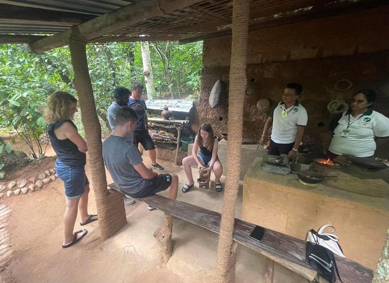 A group of people around an outdoor cooking area with a grill and cooking utensils. 3
