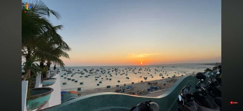 A beach with numerous boats and a sunset in the background. 3