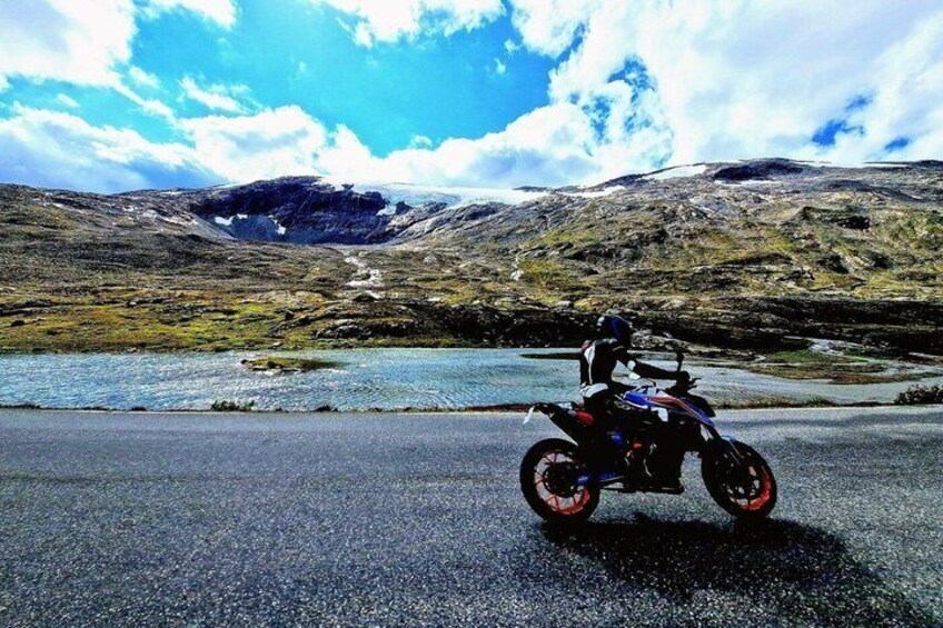 A motorcycle on a road with a mountainous landscape and a body of water in the background. 5