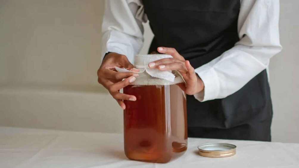A person sealing a jar with a cloth. 2