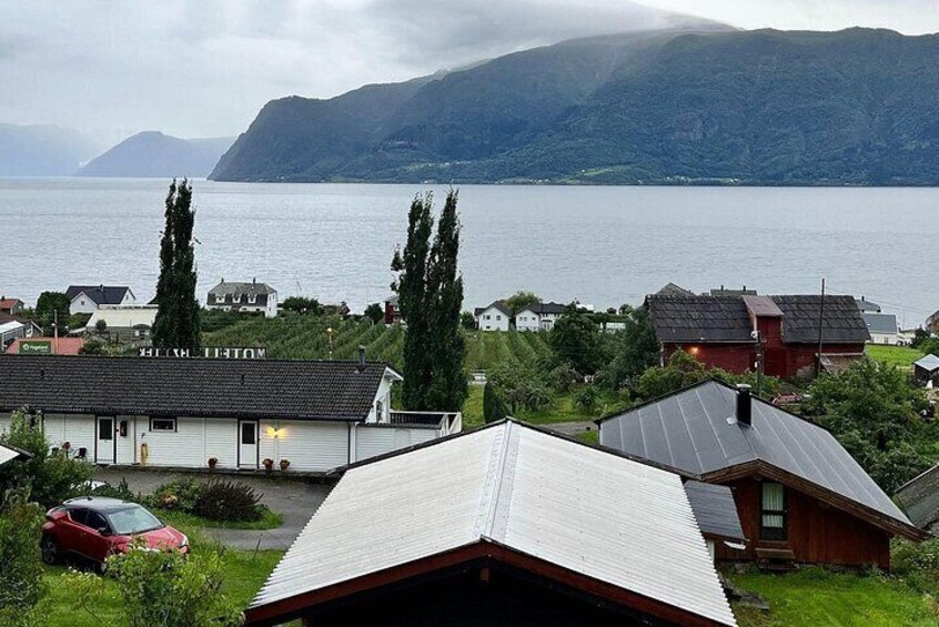 A coastal village with houses, a red car, and a mountain in the background. 4