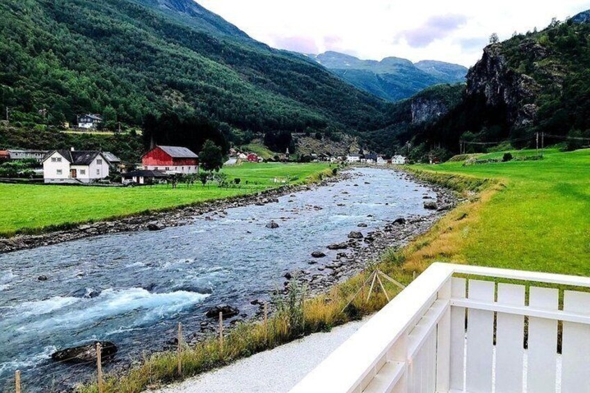 A river flowing through a valley with houses on the banks and mountains in the background. 2