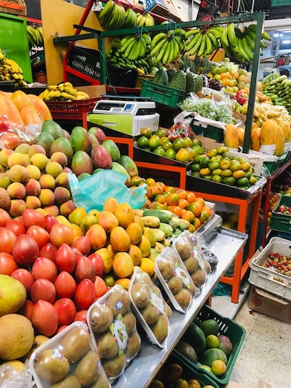 A fruit market with various fruits like mangoes, kiwis, and bananas. 1