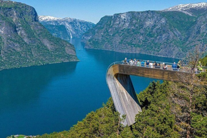 A wooden bridge over a deep fjord with a waterfall in the background. 1