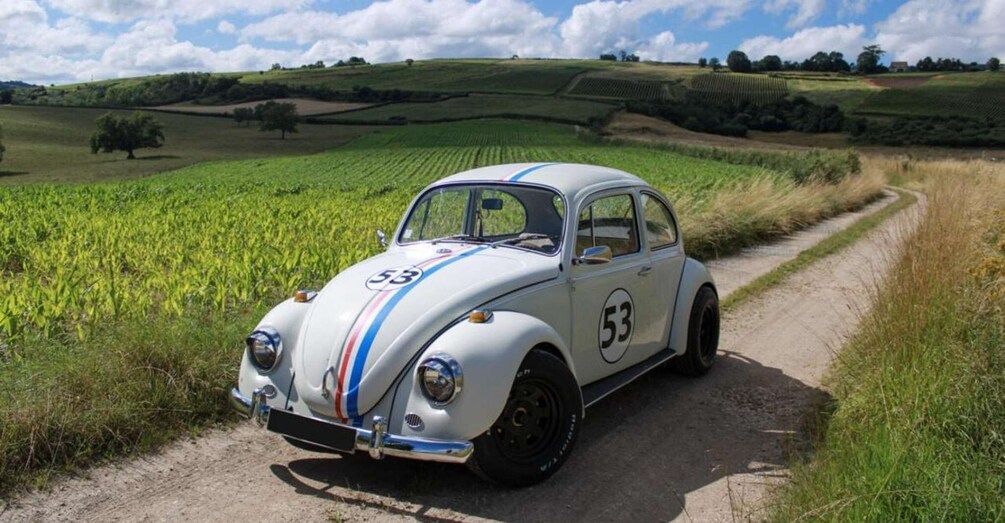 A vintage car with racing number 53 parked on a rural road. 4