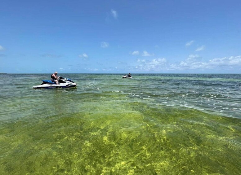 Two jet skis on clear ocean water with a blue sky. 3