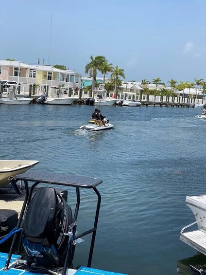 A waterway with boats, a jet ski, and waterfront buildings. 2