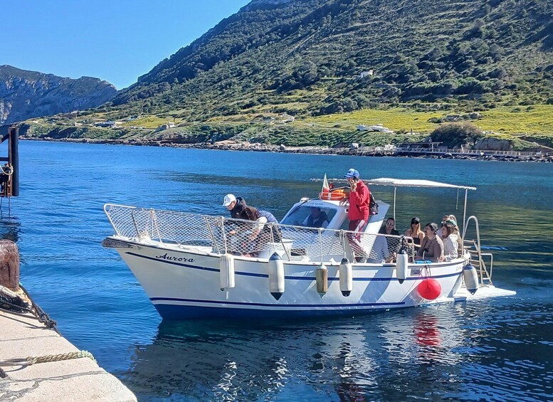 A boat named 'Aurora' docked at a pier with passengers on board, surrounded by a mountainous landscape. 1
