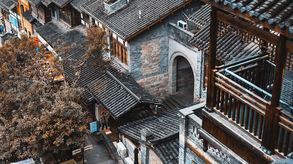 A traditional Chinese courtyard with tiled roofs, stone walls, and a wooden gate. 2