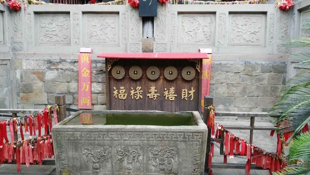 A stone structure with a wooden door, red ribbons, and Chinese characters. 3