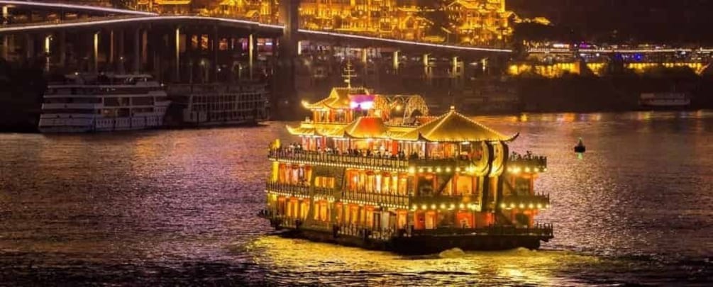 A brightly lit riverboat with traditional architecture, a bridge in the background, and a cityscape with illuminated buildings. 5