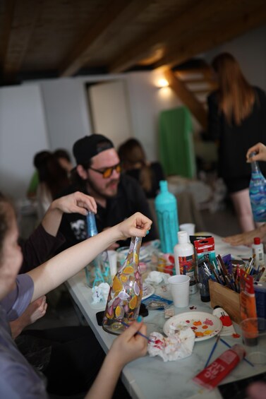 People sitting at a table with paint supplies and a water bottle. 3