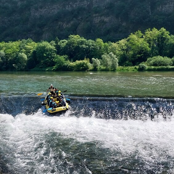 A group of people in a yellow raft navigating a river with rapids. 1
