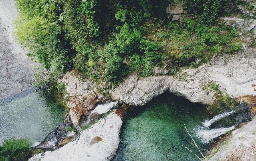 A rocky landscape with a clear water stream flowing through a natural arch. 5