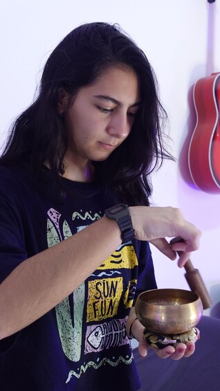 A person holding a bowl and a mallet, likely preparing to play a musical instrument. 3