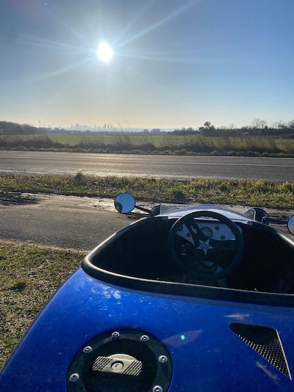 A blue sports car parked on a road with a city skyline in the background. 5