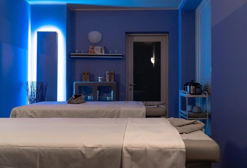 A room with two beds, a door, a shelf with items, and a wall with a light. 4
