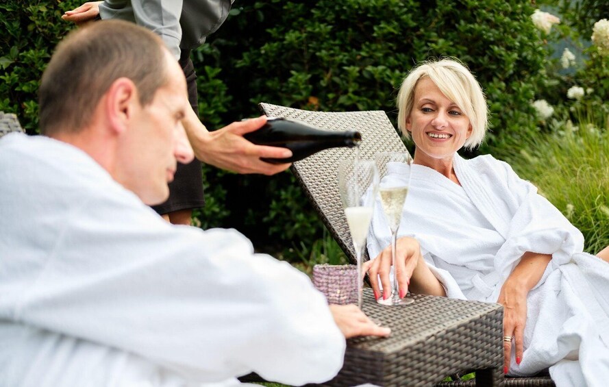 A person in a white robe sitting at a table with champagne glasses. 1