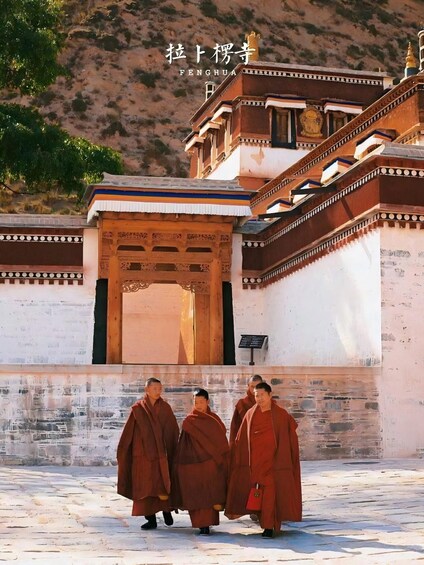 Monks walking in front of a traditional Tibetan building with a golden spire. 3