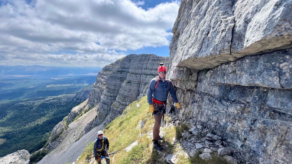 A person rappelling down a rocky mountain slope with a scenic view of the valley below. 1
