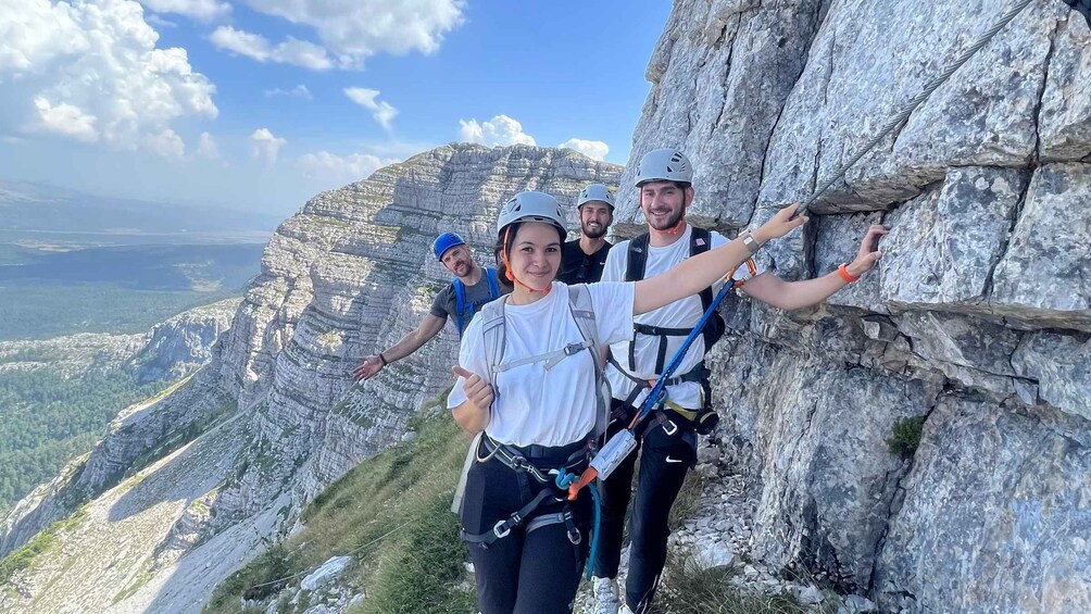 A group of people rappelling down a rocky cliff with a mountainous landscape in the background. 4