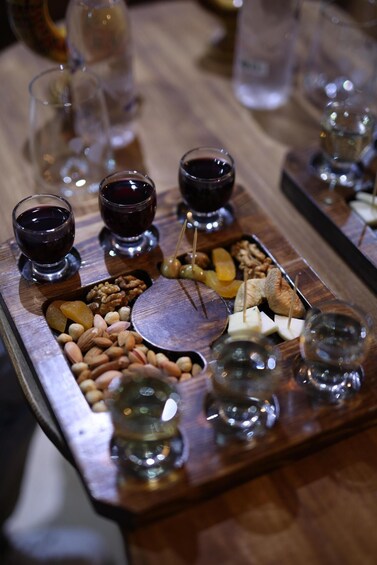 A charcuterie board with various cheeses, nuts, and fruits, accompanied by glasses of red wine. 4