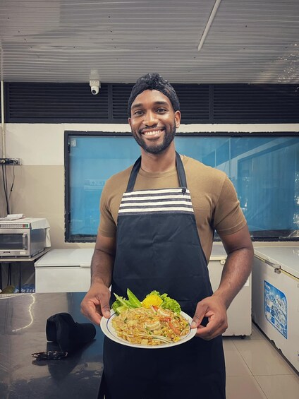 A person holding a plate of food in a kitchen. 2