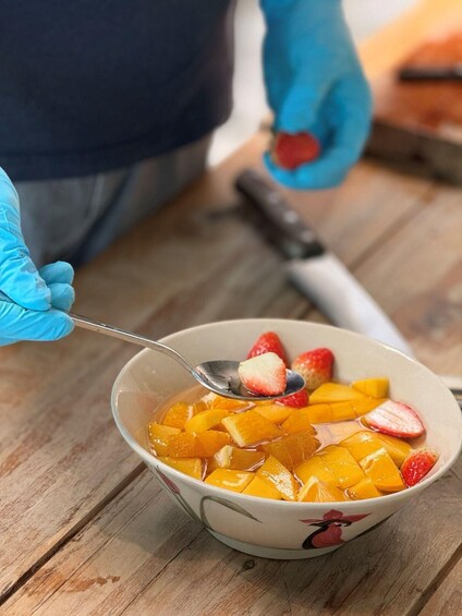 A bowl of fruit with a spoonful being lifted, on a wooden surface. 5