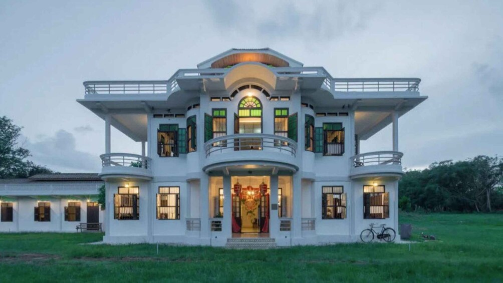 A large, white, two-story house with green shutters and a balcony. 1