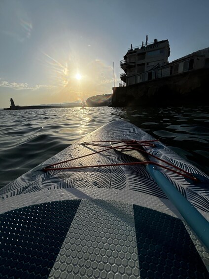 A boat's deck with a wake, calm water, and a distant shoreline with buildings. 2