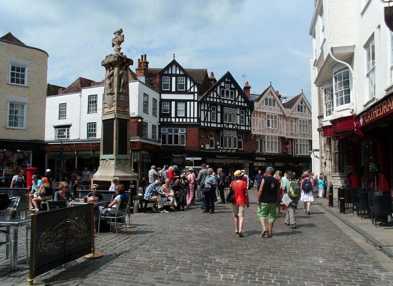 Una plaza animada con edificios históricos, una estatua destacada y gente caminando y sentada. 2