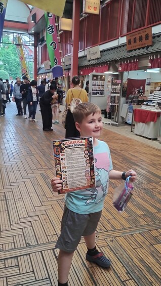A child holding a sign with 'ASAKUSA NINJA MISSION' written on it. 5