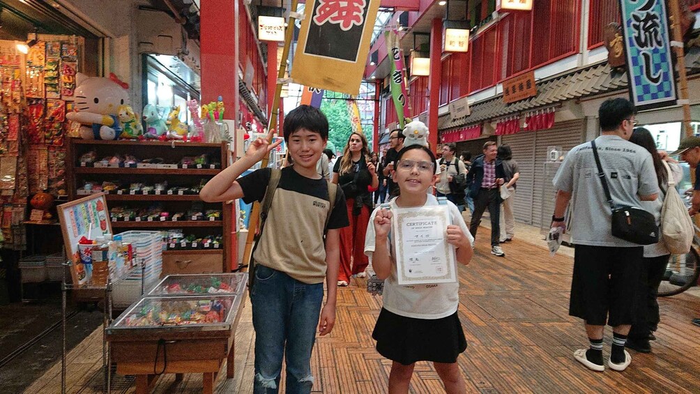 A crowded indoor market with various stalls and a Hello Kitty statue. 1