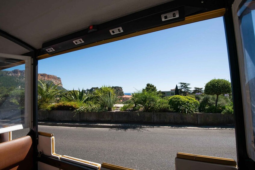 A bus interior with a view of a road, greenery, and distant buildings. 5