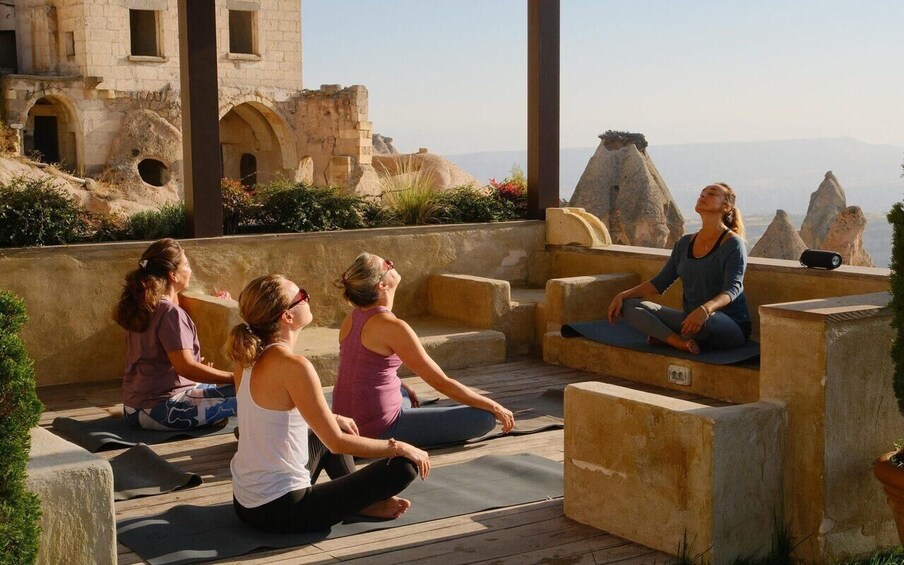 A group of people practicing yoga on a wooden deck with a historic building in the background. 2