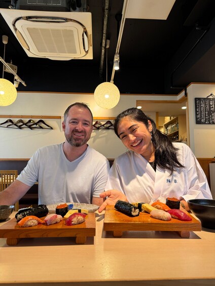 Two people seated at a table with various sushi dishes in a restaurant. 2