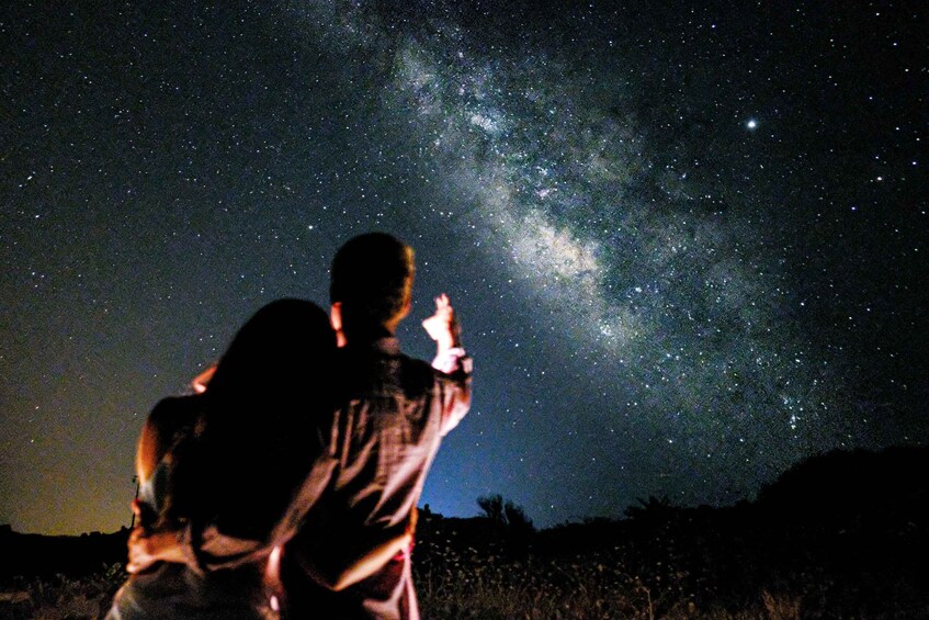 Two people observing the night sky, with the Milky Way visible. 1