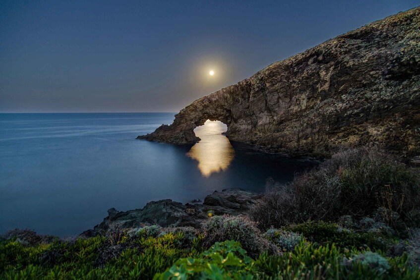 A moonlit coastal scene with a rocky cliff and a calm sea. 3