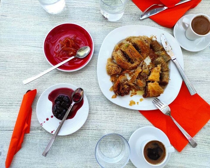 A table with a plate of food, a bowl of jam, a cup of coffee, and a glass of water. 3
