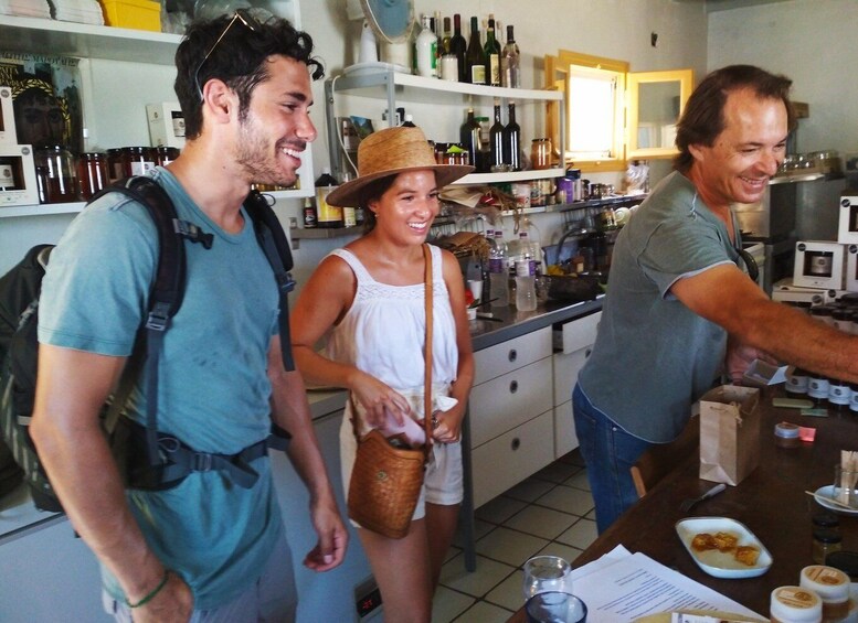 Three people in a kitchen with wine bottles and a coffee machine. 2