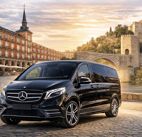 A black Mercedes-Benz van parked on a cobblestone street with a historic bridge and buildings in the background. 2