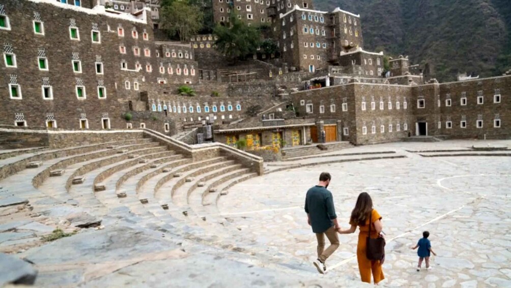 A historical stone amphitheater with a family walking on its steps. 4