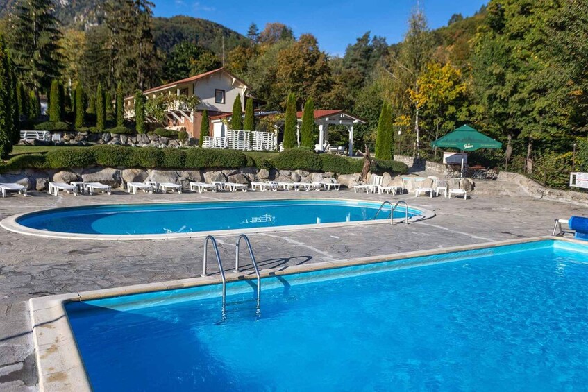A swimming pool with lounge chairs and a gazebo in a mountainous area. 5