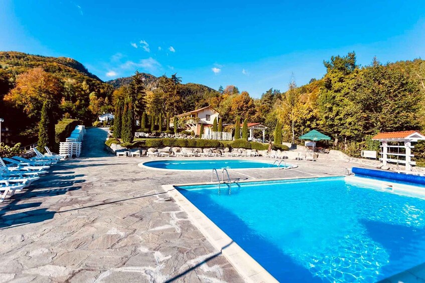 A swimming pool with lounge chairs and a gazebo in a mountainous area. 1