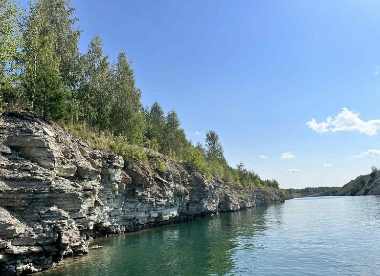 A riverbank with layered rock formations and dense green foliage. 2
