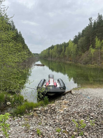A rowboat tied to a rocky shore with a forested river in the background. 5