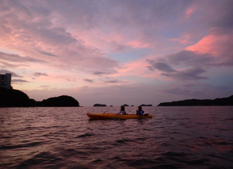 A sunset over water with a yellow kayak and two people. 5